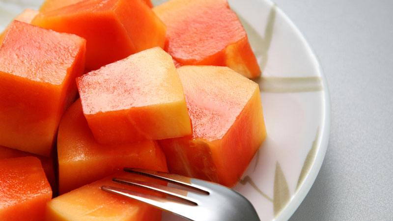 A plate of cut up cantaloupe next to a fork.